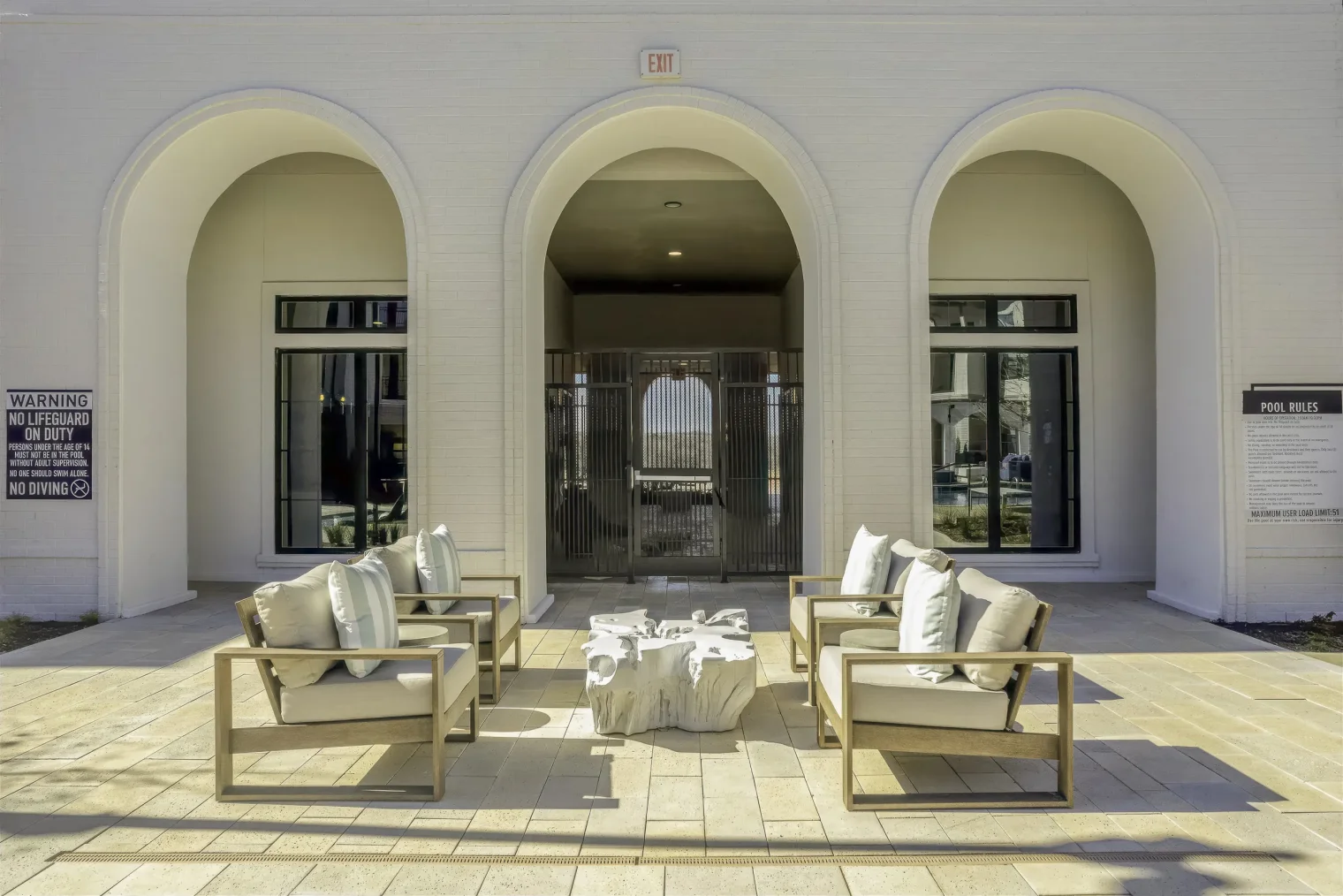 Outdoor lounge seating beneath arched patio openings at the Parker at Walsh pool courtyard