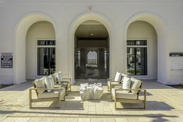Outdoor lounge seating beneath arched patio openings at the Parker at Walsh pool courtyard