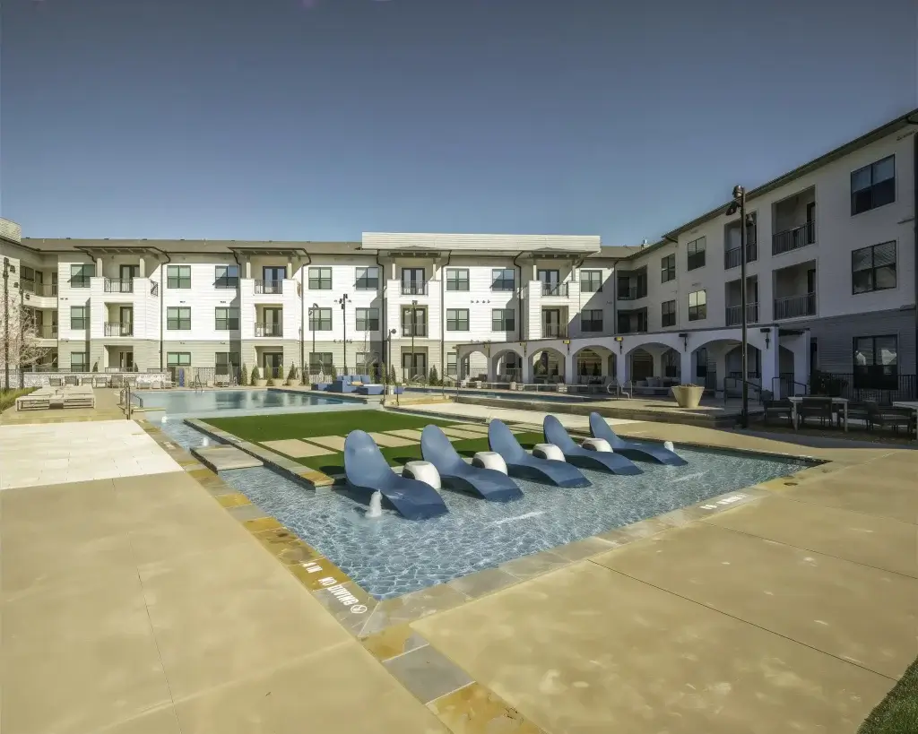 Pool courtyard with sun shelf loungers surrounded by Parker at Walsh apartment homes in Aledo